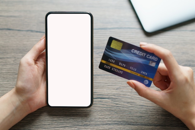 Manos de mujer con tarjeta de crédito y pantalla en blanco de teléfono inteligente