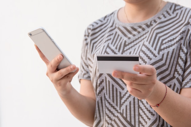 Manos de mujer con tarjeta de crédito y con teléfono inteligente para pago en línea, compras en línea,