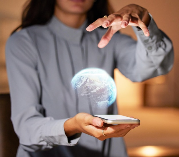 Foto manos de mujer y teléfono con holograma 3d de globo para redes de comunicación global o tecnología en la noche mano de mujer sosteniendo teléfono inteligente con tierra holográfica para innovación tecnológica futurista