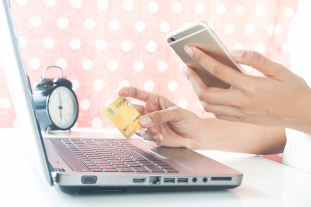 Foto manos de mujer con teléfono móvil y tarjeta de crédito de plástico. pago electrónico. las compras en línea