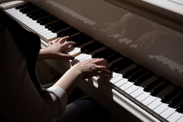 Foto manos de mujer tocando un piano, instrumento musical.