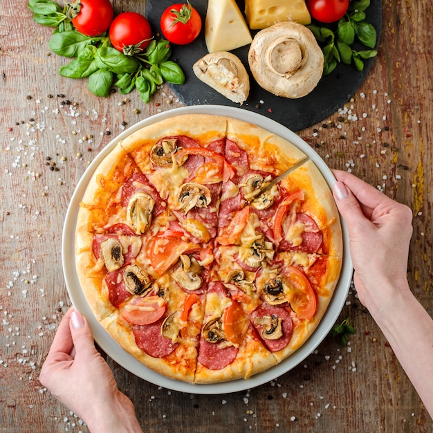 Manos de mujer toma pizza en un plato