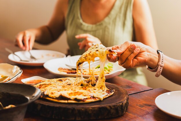 Manos de mujer tomando porciones de pizza con amigos