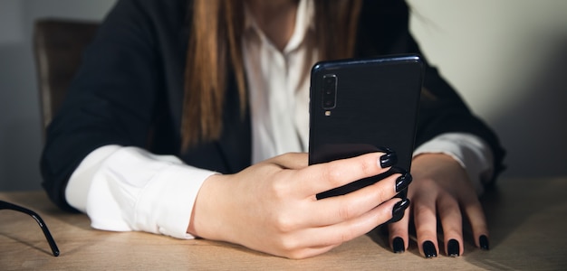 Manos de mujer trabajadora con teléfono en la oficina