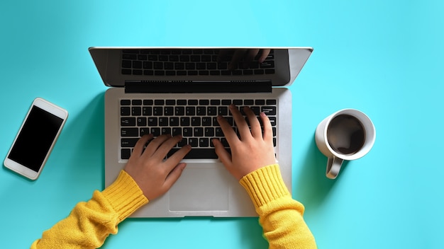 Manos de mujer usando una computadora portátil en el fondo de colores