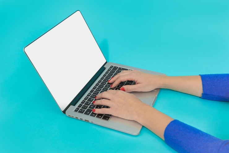 Foto manos de mujer usando computadora portátil con pantalla en blanco sobre fondo azul concepto moderno de espacio de trabajo