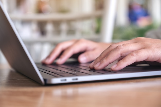 Manos de mujer usando y escribiendo en el teclado del portátil sobre la mesa