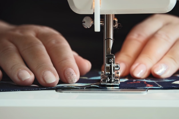 Manos de mujer usando la máquina de coser en casa durante la cuarentena