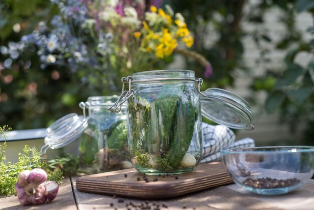 Las manos de una mujer vierten agua hervida en un frasco con pepinos encurtidos