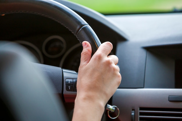 Manos de mujer en el volante de un automóvil.