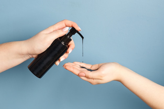 Manos de mujeres aplicando aceite de limpieza negro con carbón para limpiar la piel
