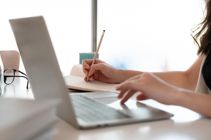 Foto las manos de las mujeres cercanas con el portátil, la computadora portátil, el cuaderno y el bolígrafo tomando notas en la oficina de negocios