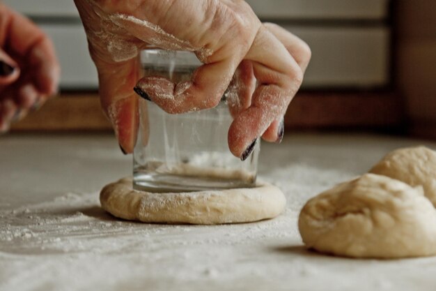 Foto las manos de las mujeres cortan la masa amasada cruda en pedazos en el fondo del plato de cocción interior de la cocina