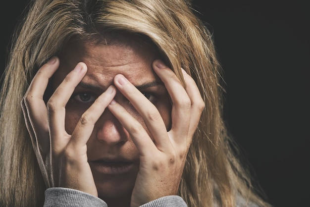 Las manos de las mujeres se cubren o se enfrentan al estrés en el fondo negro en la comunidad de asilo de salud mental o en el hospital de psicología de la esquizofrenia. Ansiedad, zoom, agotamiento o depresión por miedo o asesoramiento al paciente asustado.