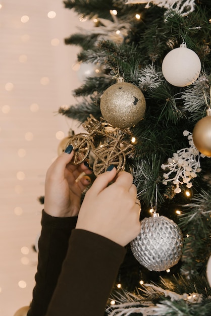 Las manos de las mujeres decoran el árbol de Navidad con globos.