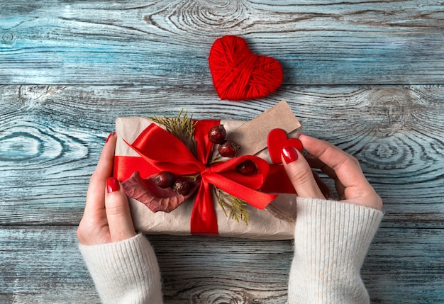 Las manos de las mujeres decoran una caja de regalo sobre un fondo de madera.