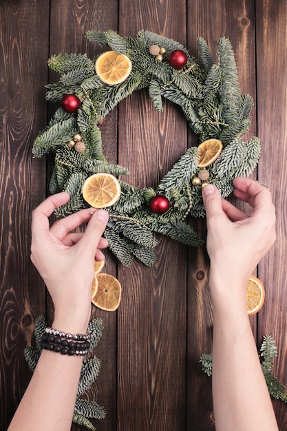 Las manos de las mujeres decoran una corona de Navidad