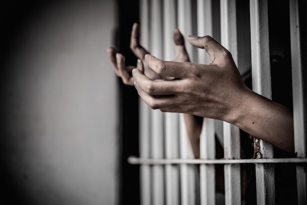 Las manos de las mujeres desesperadas por atrapar el concepto de prisionero de hierro la gente de Tailandia espera ser libre si el violador de la ley sería arrestado y encarcelado