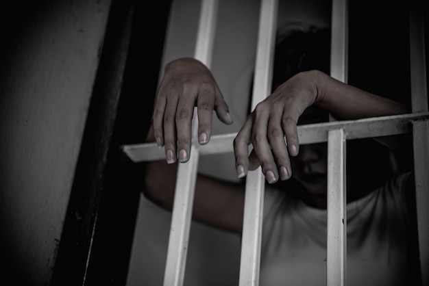 Las manos de las mujeres desesperadas por atrapar el concepto de prisionero de hierro la gente de Tailandia espera ser libre si el violador de la ley sería arrestado y encarcelado