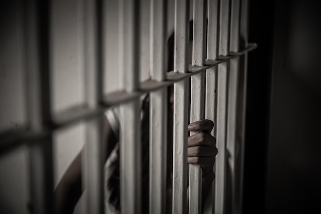Las manos de las mujeres desesperadas por atrapar el concepto de prisionero de hierro la gente de Tailandia espera ser libre si el violador de la ley sería arrestado y encarcelado