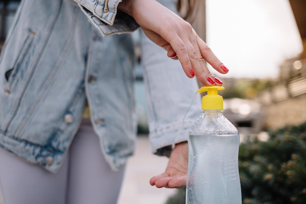 Manos de las mujeres con dispensador de bomba de gel desinfectante de manos para lavar