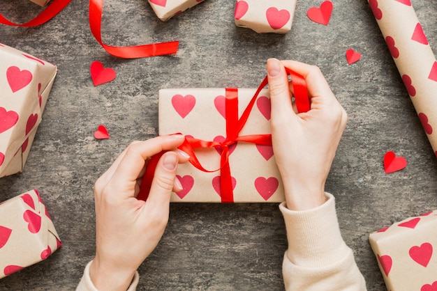 Las manos de las mujeres empacan regalos y hacen decoraciones para las vacaciones vista superior cumpleaños y regalo de San Valentín