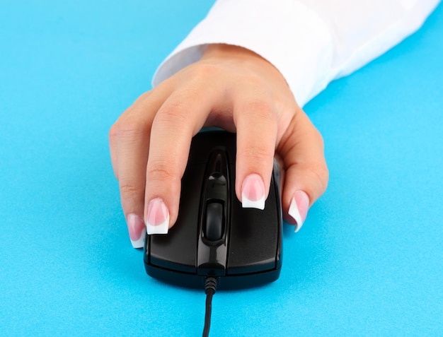 Las manos de las mujeres empujando las teclas del ratón de la PC en primer plano de fondo azul