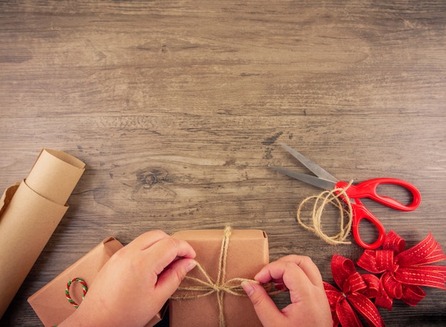 Las manos de las mujeres envuelven cajas de regalo de Navidad con herramientas de envoltura aplanadas