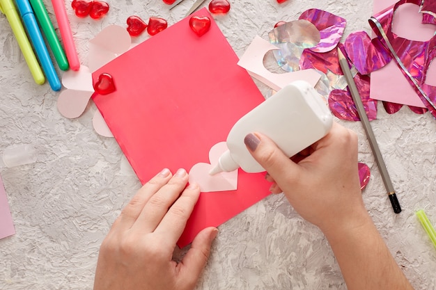 Las manos de las mujeres hacen una tarjeta para el día de san valentín