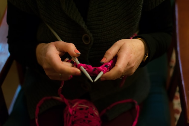 Las manos de las mujeres haciendo crochet en un sofá.