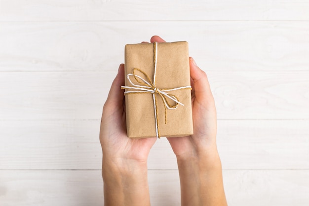 Manos de mujeres haciendo un regalo de papel artesanal.