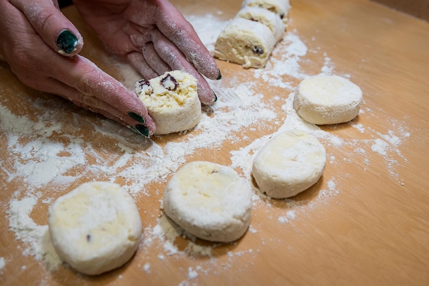 Las manos de las mujeres en harina hacen una forma de tarta de queso a partir de la masa para preparar y freír en una sartén