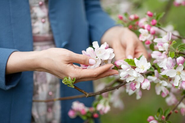 Manos de mujeres hermosas sosteniendo jardín de rama de árbol de manzana en flor en jardín de primavera. Disfruta de la naturaleza. Concepto de primavera. Cerrar imagen