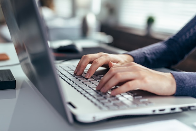 Foto manos de las mujeres en un primer plano del teclado de la computadora portátil.