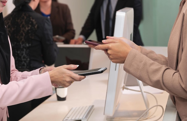 Manos de las mujeres del primer que sostienen el teléfono móvil para las transacciones de pago digitales inalámbricas en el servicio del mostrador. Concepto de pago de tecnología sin contacto del cliente