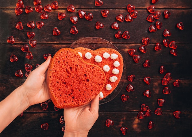 Las manos de las mujeres recogen un bizcocho rojo en forma de corazón