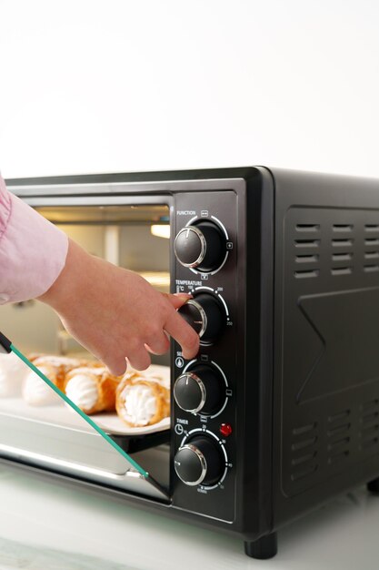 Las manos de las mujeres sacando panadería fresca del mini horno