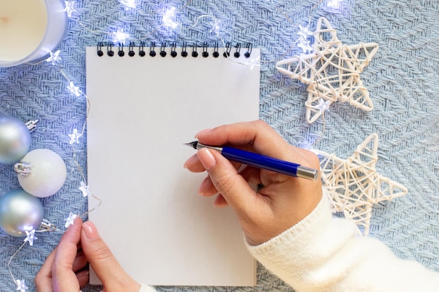 Las manos de las mujeres sobre una hoja blanca de cuaderno sostienen una pluma estilográfica azul