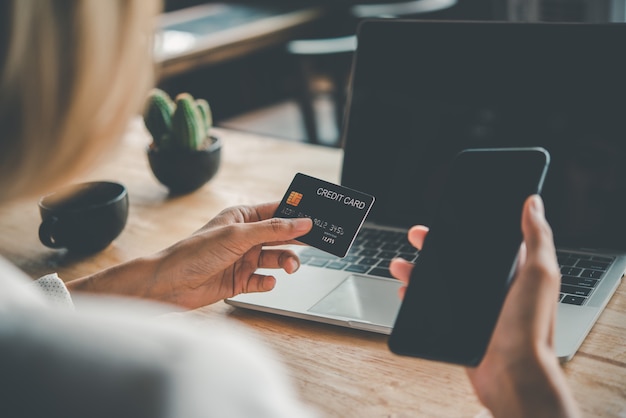 Manos de mujeres sosteniendo una tarjeta de crédito y trabajo en computadora portátil Pago en línea para compras en línea