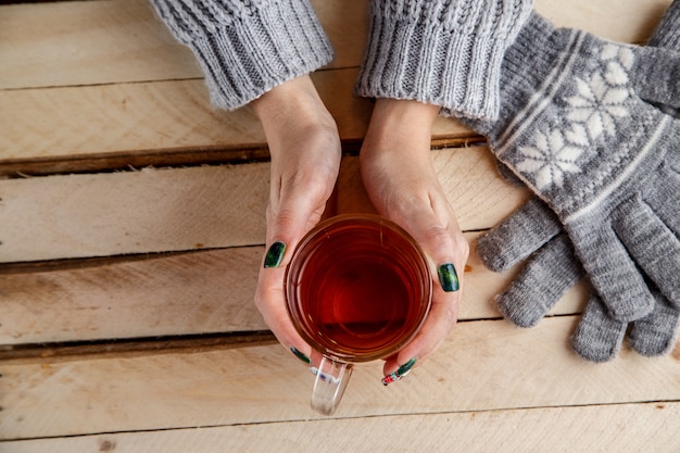 Manos de mujeres sosteniendo una taza vintage sobre una mesa de madera