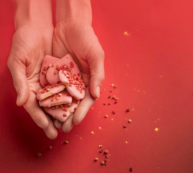 Las manos de las mujeres sostienen galletas en forma de corazón con bayas secas para el día de San Valentín, enfoque selectivo