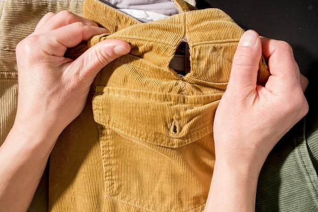 Las manos de las mujeres sostienen pantalones de pana rotos. Compras