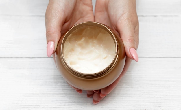 Las manos de las mujeres sostienen un recipiente de crema para el cuidado de la piel de la cara o el cuerpo productos cosméticos naturales Cuidado moderno de la piel