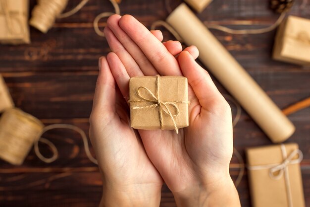 Foto las manos de las mujeres sostienen un regalo de papel artesanal.