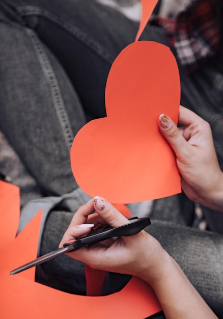 las manos de las mujeres sostienen tijeras y están listas para el corazón de papel hecho a mano en el Día de San Valentín. De cerca