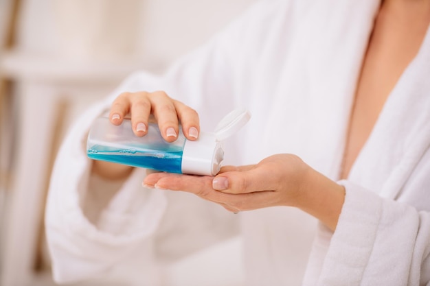 Las manos de las mujeres sostienen tónico para quitar el maquillaje.