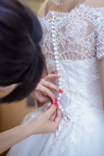 Las manos de las mujeres sujetan el vestido de dama de honor en los botones pequeños