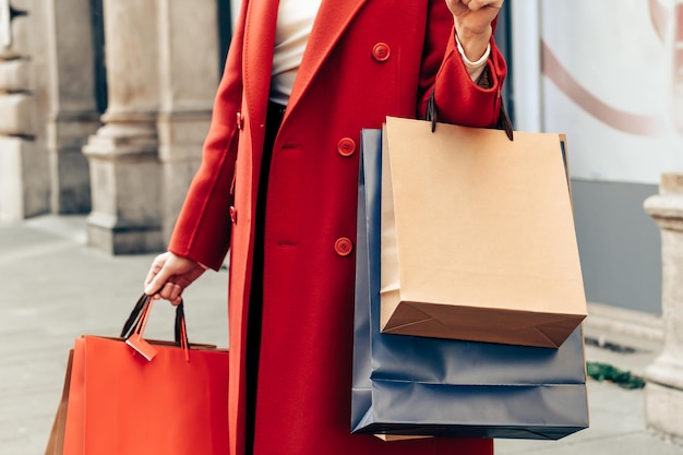 Las manos de las mujeres de la temporada de rebajas sostienen muchas bolsas de compras.