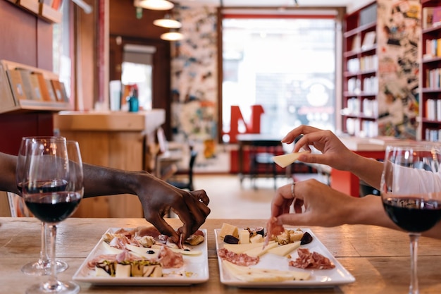 Manos multiétnicas recogiendo comida de los platos en la mesa en el restaurante café tapas concepto de tiempo de aperitivo