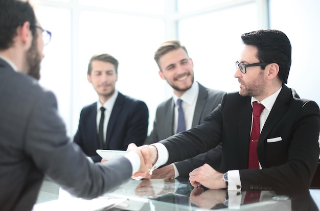 Manos de negocios dándose la mano sentado en la oficina Deskconcept de asociación